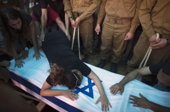 The mother of Israeli soldier Tal Yifrah mourns over his flag-covered coffin during his funeral in Rishon Lezion near Tel Aviv